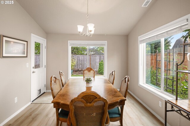 dining area with vaulted ceiling, light wood-type flooring, a chandelier, and a wealth of natural light