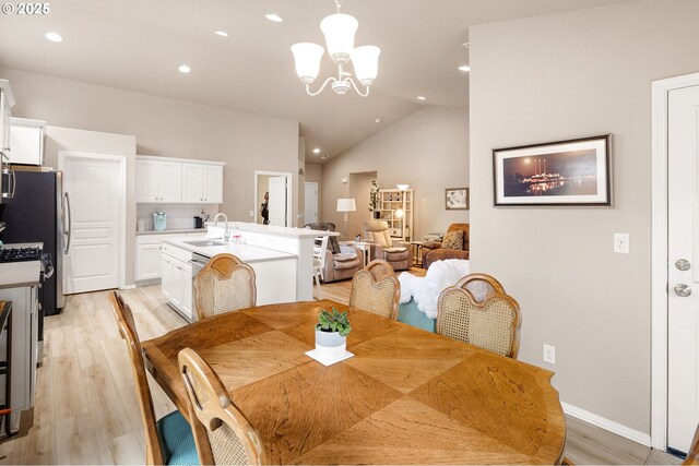 dining area with light wood-style floors, recessed lighting, vaulted ceiling, and an inviting chandelier