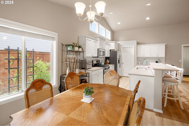 dining room with light wood-style floors, recessed lighting, a notable chandelier, and high vaulted ceiling