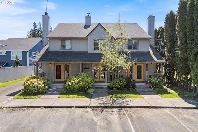 view of front of house featuring a porch, a chimney, fence, and a shingled roof