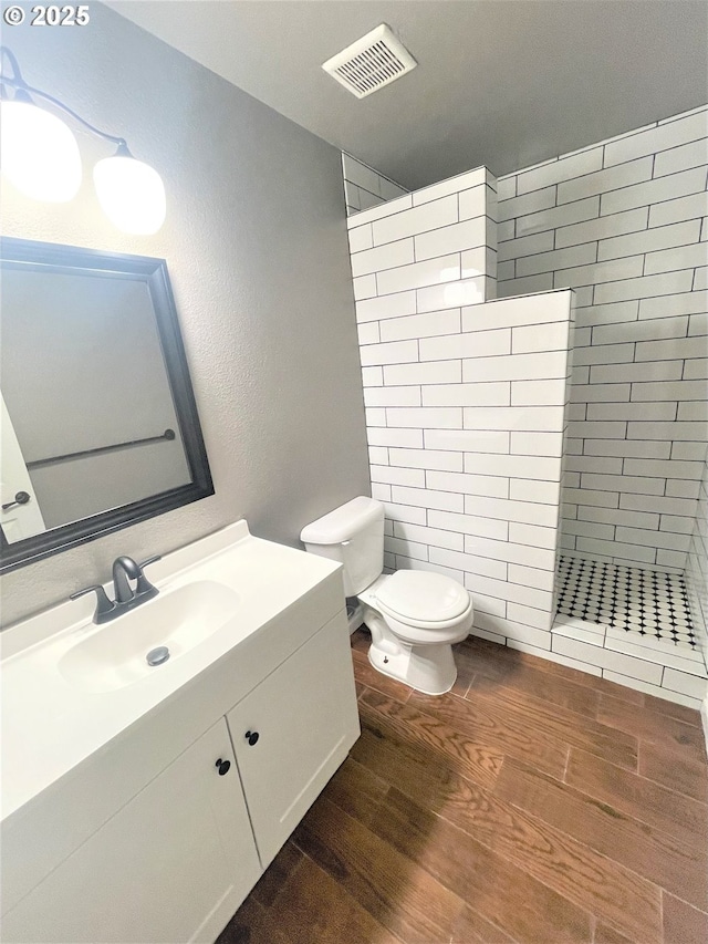 bathroom with wood finished floors, visible vents, a walk in shower, and toilet