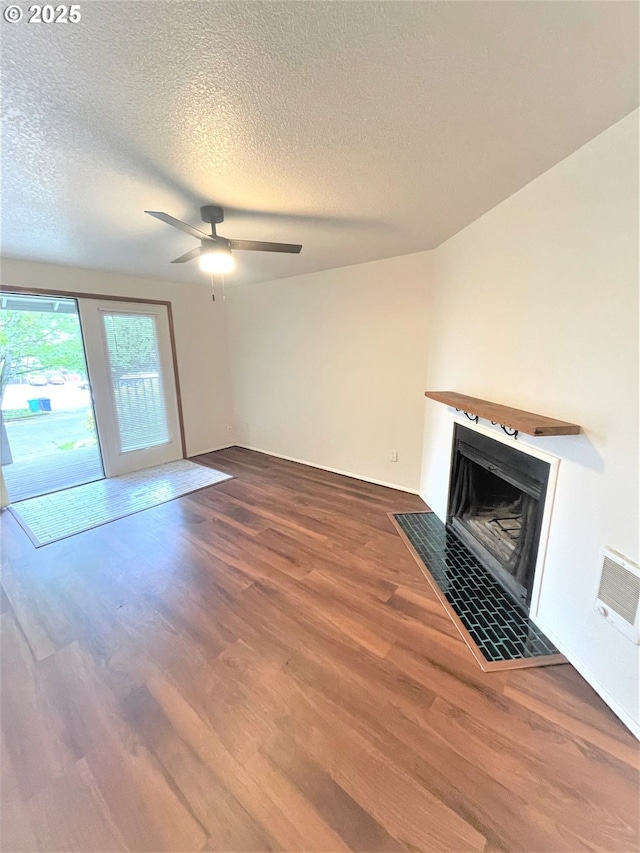 unfurnished living room with a fireplace with flush hearth, a ceiling fan, wood finished floors, and a textured ceiling