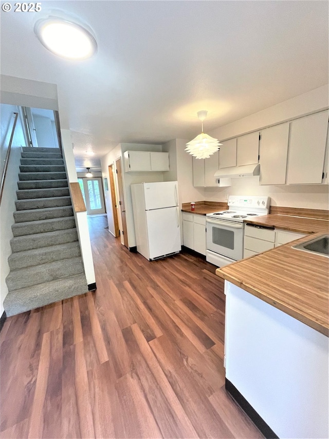 kitchen featuring under cabinet range hood, a sink, dark wood-type flooring, white appliances, and wood counters