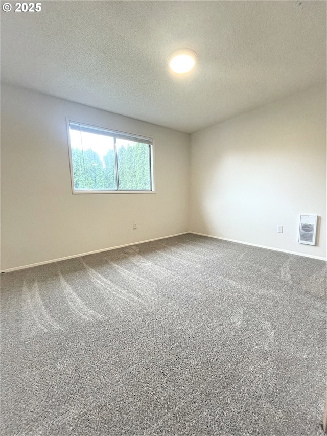 carpeted spare room featuring baseboards and a textured ceiling