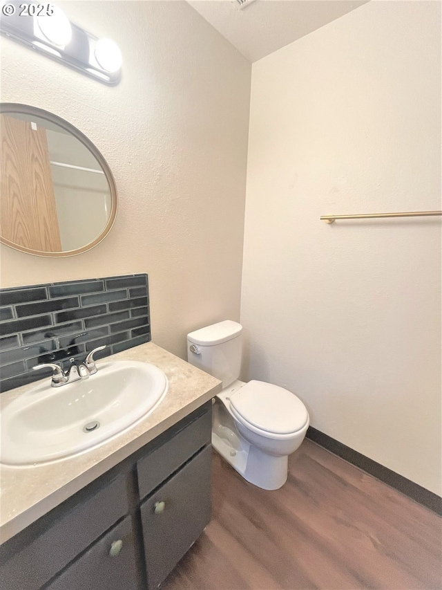 bathroom with backsplash, wood finished floors, vanity, and toilet