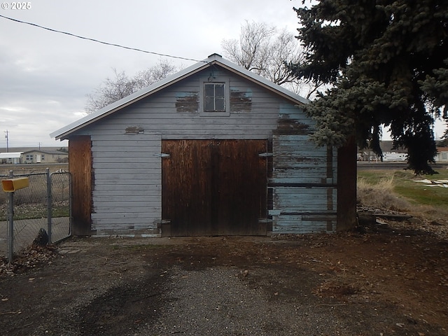 exterior space with a garage, fence, and an outbuilding