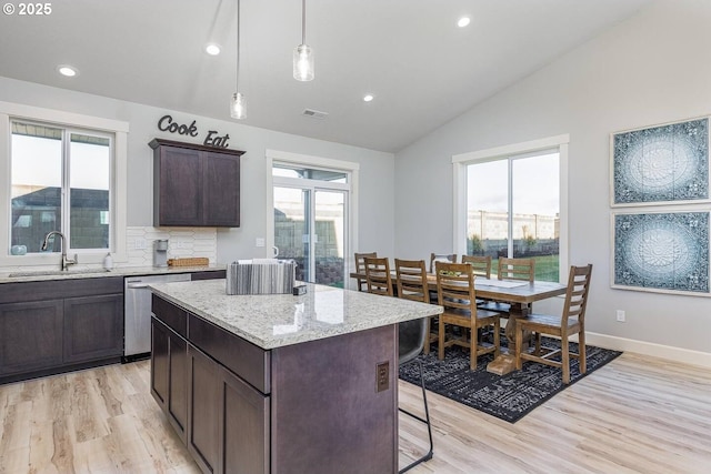 kitchen with a sink, dishwasher, vaulted ceiling, light wood-style floors, and a kitchen island