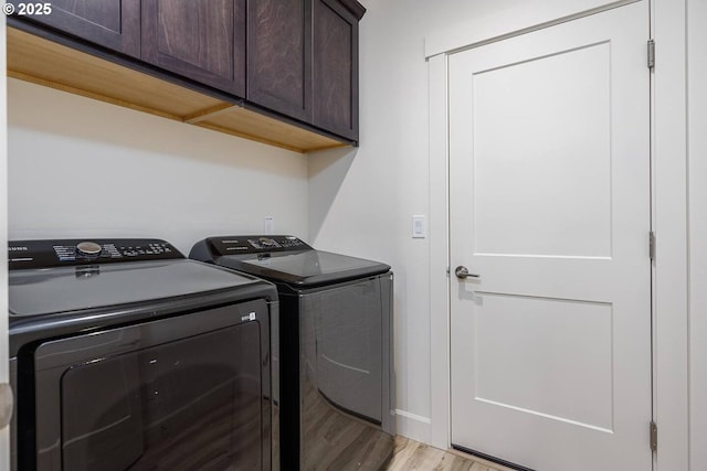 laundry room featuring cabinet space, washer and dryer, and light wood-type flooring