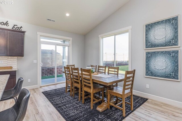 dining room featuring lofted ceiling, light wood-style floors, baseboards, and recessed lighting