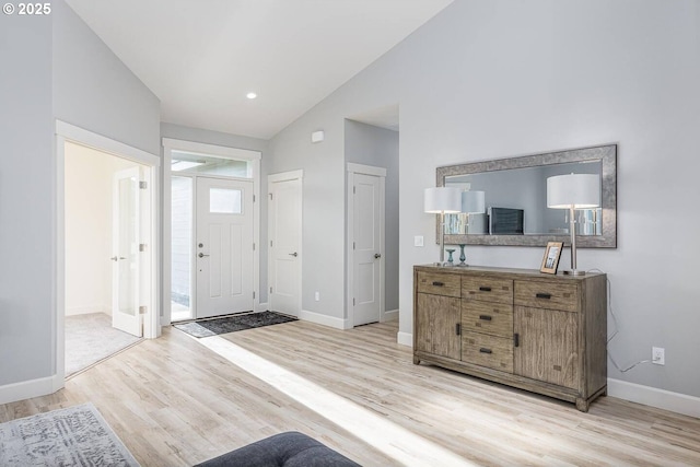 foyer featuring light wood-type flooring, baseboards, and high vaulted ceiling