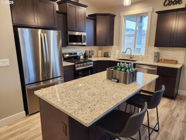 kitchen with appliances with stainless steel finishes, a sink, baseboards, and dark brown cabinets