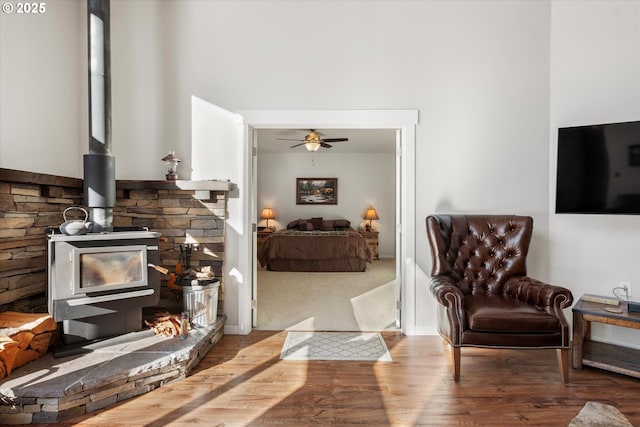 living room featuring ceiling fan, a wood stove, and wood-type flooring