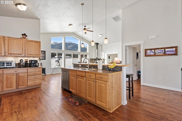 kitchen featuring stainless steel dishwasher, a kitchen bar, sink, hanging light fixtures, and dark hardwood / wood-style flooring