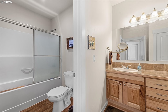 full bathroom with toilet, enclosed tub / shower combo, hardwood / wood-style flooring, and vanity