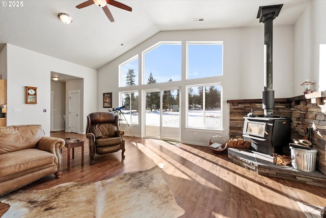 living room featuring ceiling fan, a wood stove, hardwood / wood-style floors, and lofted ceiling