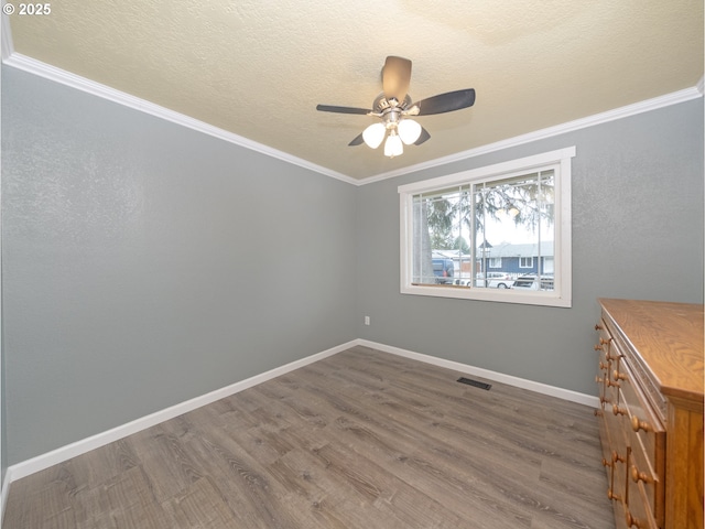 empty room featuring ceiling fan, ornamental molding, wood-type flooring, and a textured ceiling