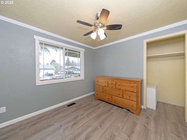 bedroom with crown molding, a textured ceiling, light wood-type flooring, a closet, and ceiling fan