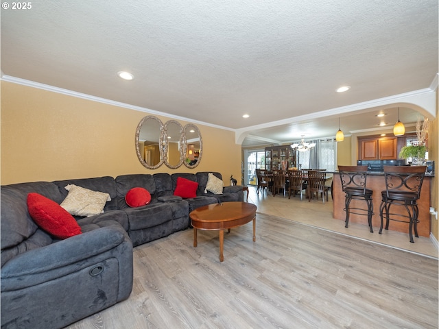 living room featuring ornamental molding, a textured ceiling, and light hardwood / wood-style flooring