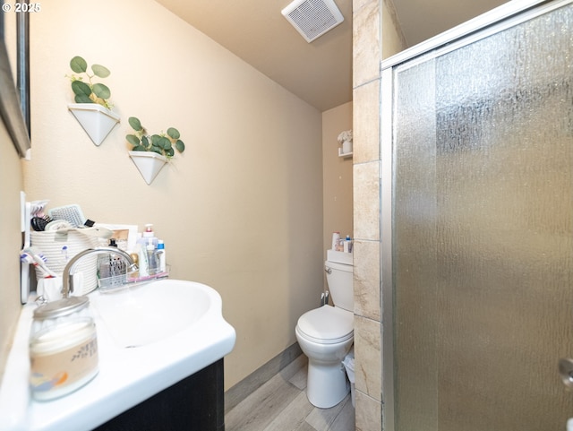 bathroom featuring a shower with door, vanity, wood-type flooring, and toilet