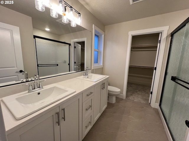 bathroom featuring a textured ceiling, toilet, a shower with door, and vanity