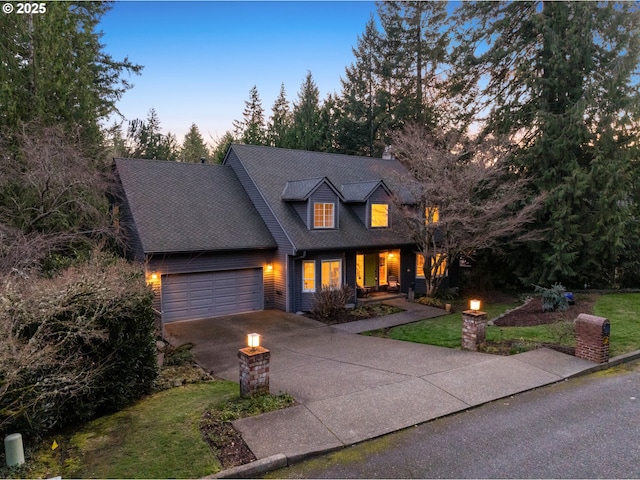 view of front of house with driveway, a yard, roof with shingles, and an attached garage