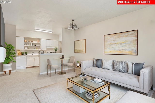 living area with an inviting chandelier, light colored carpet, baseboards, and a textured ceiling