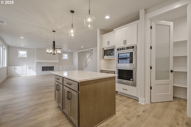 kitchen featuring light countertops, light wood-type flooring, a center island, visible vents, and appliances with stainless steel finishes