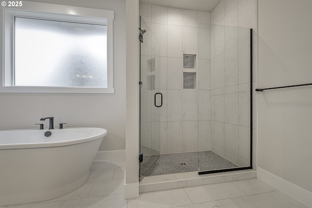 bathroom featuring baseboards, marble finish floor, a soaking tub, and a shower stall