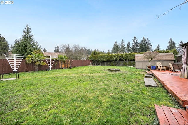 view of yard featuring a fenced backyard, a deck, an outdoor structure, and a shed