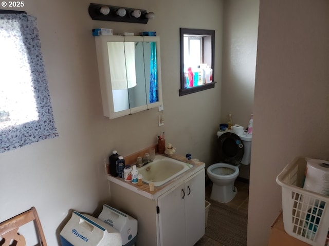 half bathroom with tile patterned flooring, toilet, and vanity