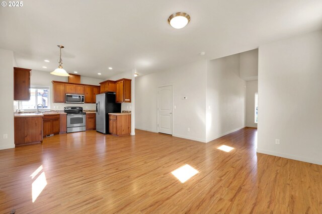 unfurnished living room featuring light wood finished floors, baseboards, a sink, and recessed lighting