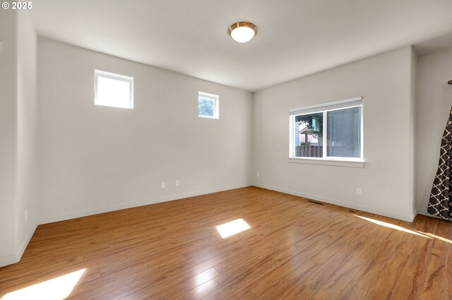 empty room with baseboards, visible vents, and wood finished floors