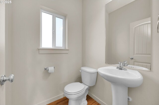 bathroom with toilet, baseboards, and wood finished floors