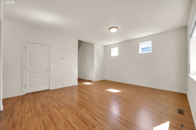 empty room with baseboards, visible vents, and light wood-style floors