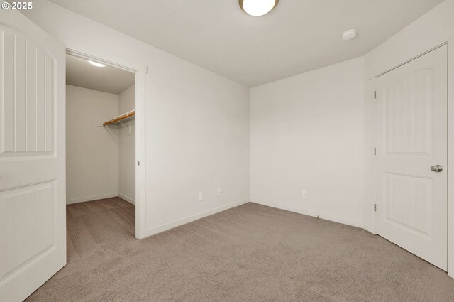 unfurnished bedroom featuring baseboards, a closet, carpet, and a walk in closet