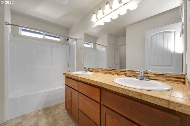 bathroom featuring a sink, double vanity, shower / tub combination, and decorative backsplash