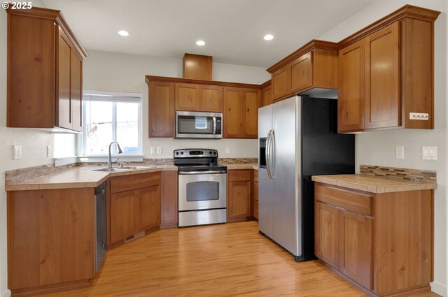 kitchen with light countertops, stainless steel appliances, light wood-style flooring, and a sink