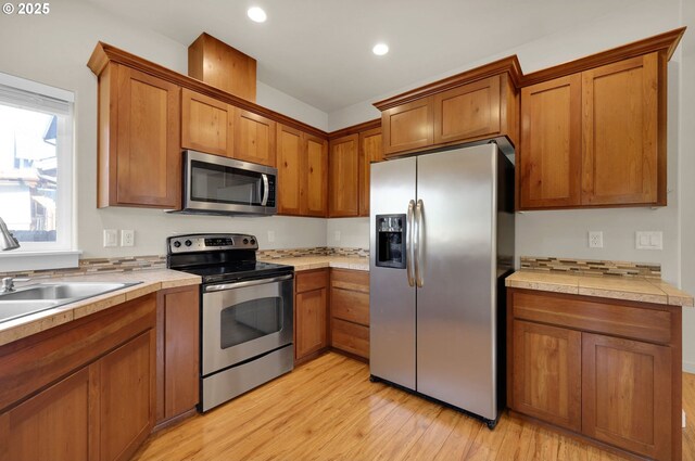 kitchen featuring light wood-style floors, stainless steel appliances, brown cabinets, and recessed lighting