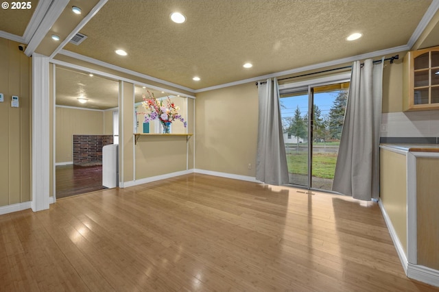 interior space featuring crown molding, light wood finished floors, and a textured ceiling