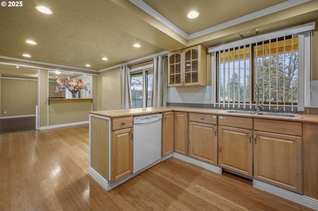 kitchen with a sink, a peninsula, white dishwasher, and light wood finished floors