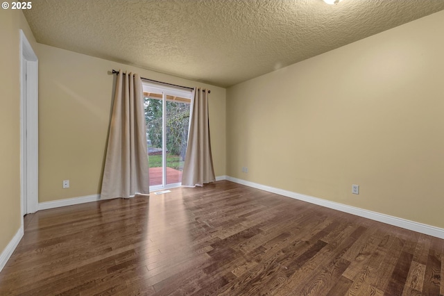 empty room featuring dark wood-type flooring, visible vents, baseboards, and a textured ceiling