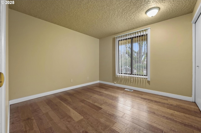 unfurnished room with visible vents, a textured ceiling, baseboards, and wood-type flooring