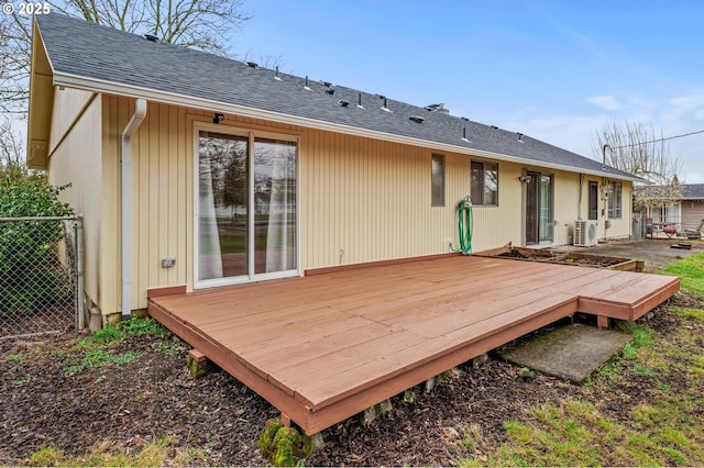 rear view of property with roof with shingles, a deck, and fence