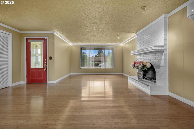 unfurnished living room featuring ornamental molding, a textured ceiling, wood finished floors, a wall unit AC, and a brick fireplace