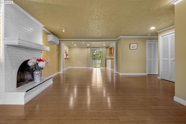 unfurnished living room with crown molding, wood finished floors, a fireplace, and a wall mounted AC