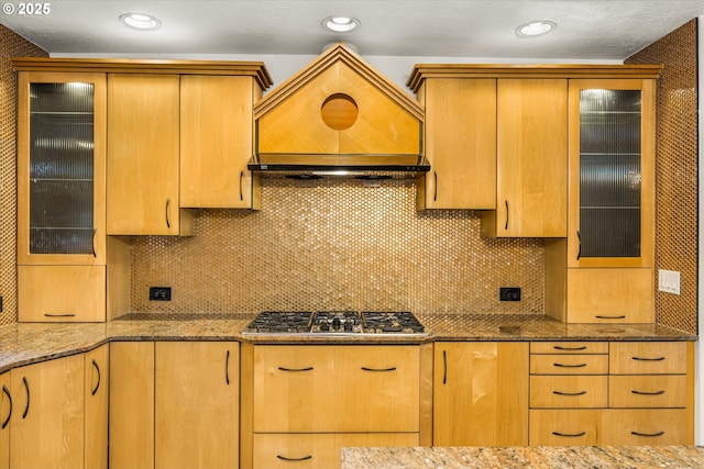 kitchen featuring stainless steel gas cooktop, tasteful backsplash, and light stone countertops