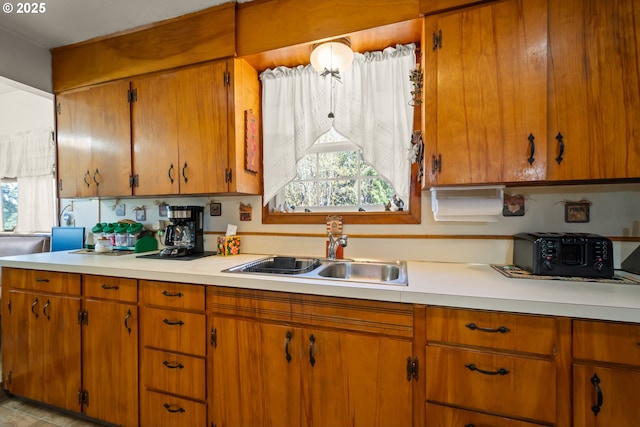 kitchen with a sink, light countertops, and brown cabinets