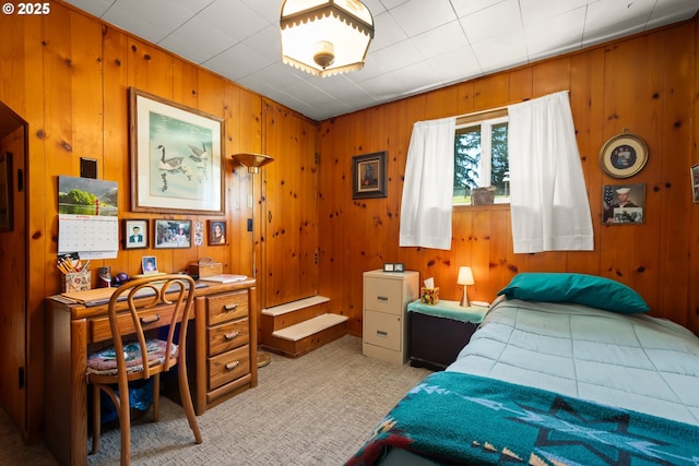 bedroom with light colored carpet, wood walls, and an office area