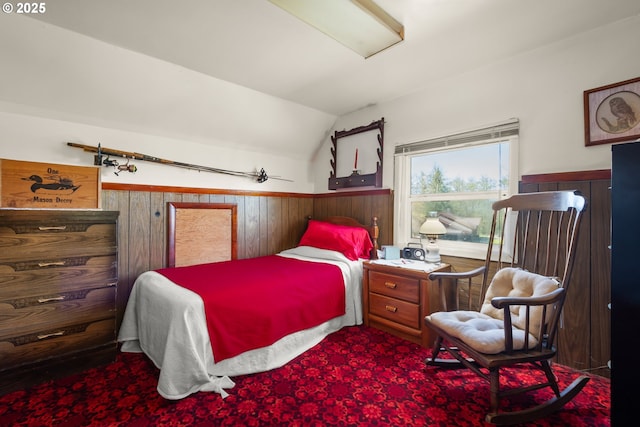 bedroom with vaulted ceiling, a wainscoted wall, wooden walls, and carpet floors