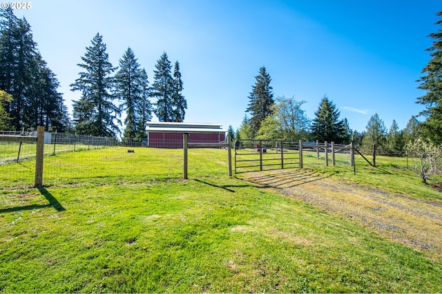 view of yard with a gate, an outbuilding, and a rural view